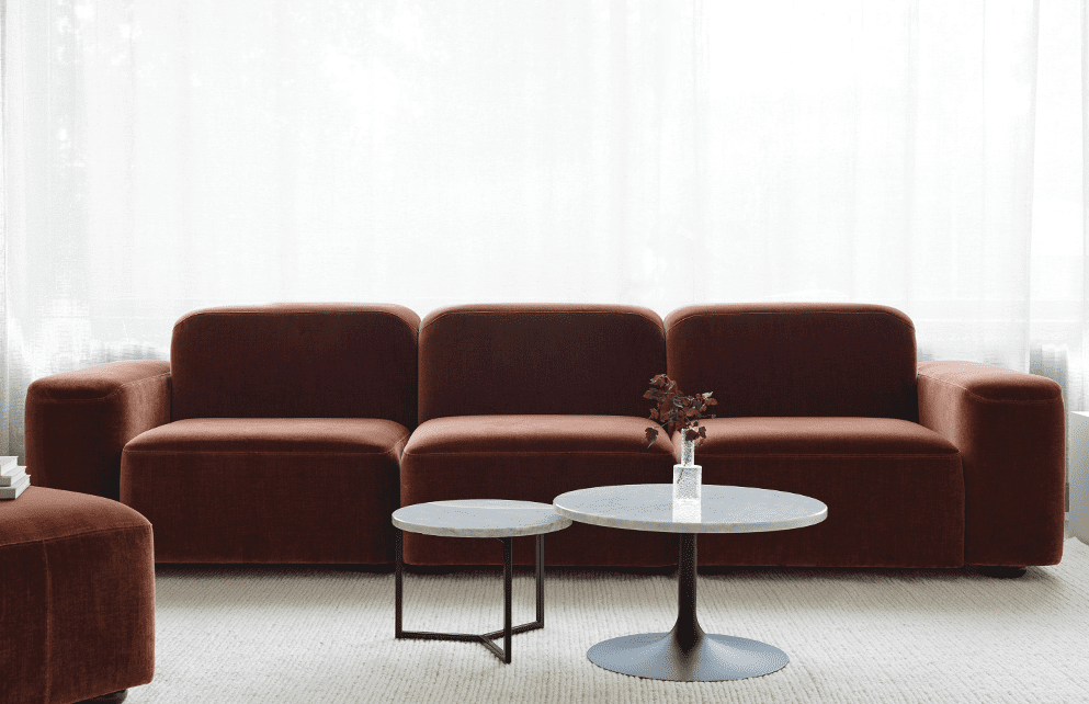 Miljöbild på modulsoffa Leon tillsammans med småborden X och Novel. Soffan har tre moduler och en puff, klädd i ett rostfärgat sammetstyg.