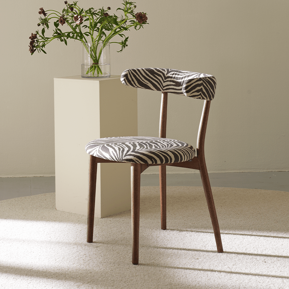 Ruth - nätt stol i ask, betsad valnöt. Stoppad sits och rygg klädd i ett zebra-mönstrat tyg.