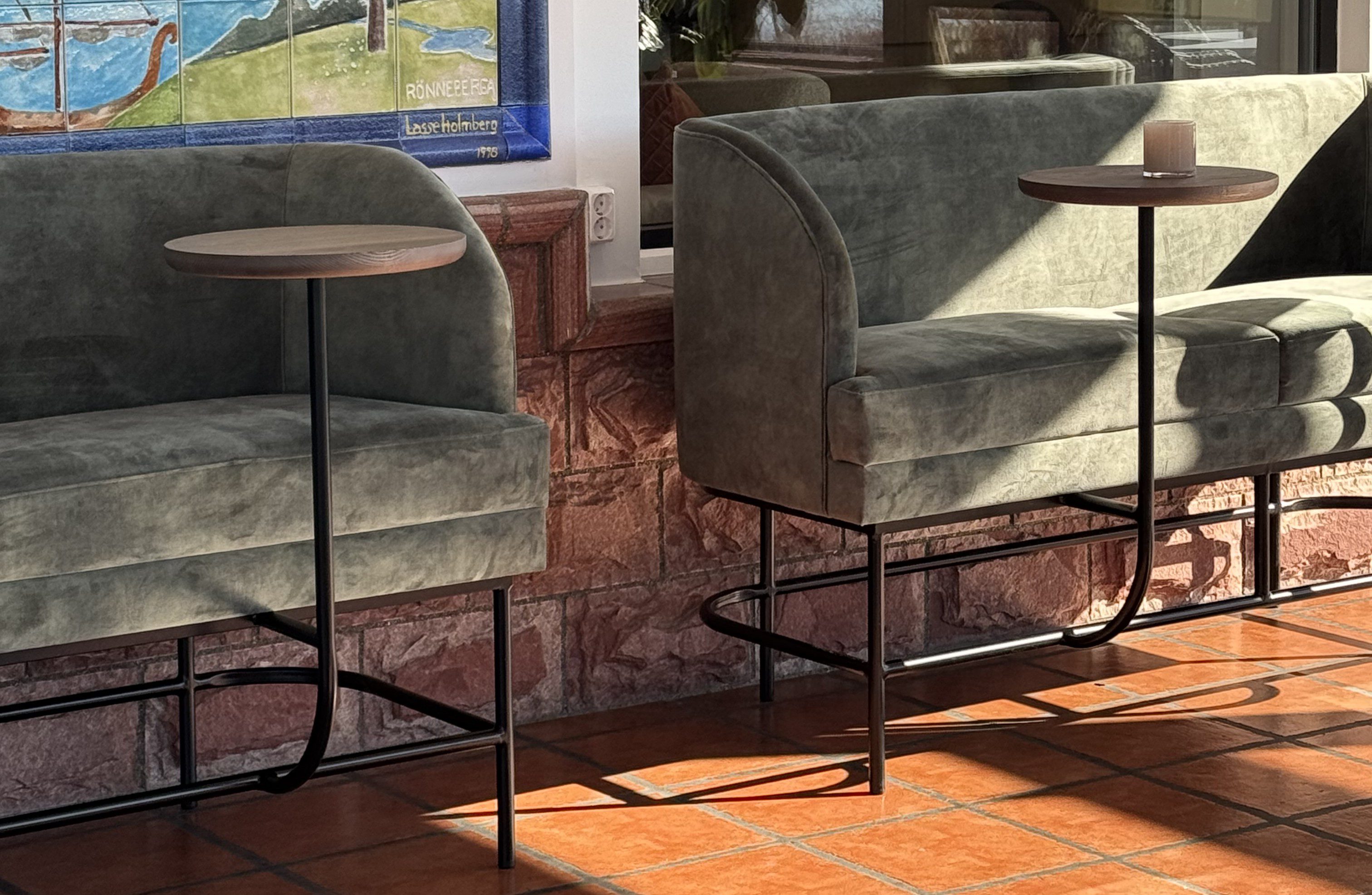 Stockholm - barsoffa i svart metall, klädd i sammet. Soffan har inbyggda små runda bord.