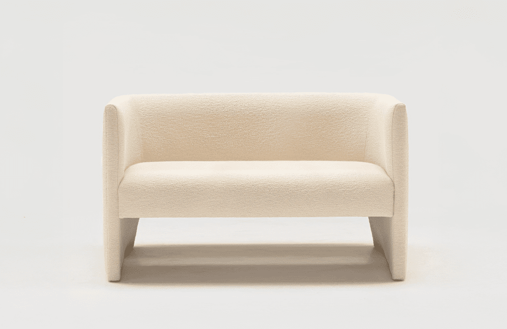 Ted Sofa - Nätt soffa med omslutande form. Ted erbjuder en perfekt balans mellan form och funktion. Mycket fint tapetserad, klädd i ett vitt boucletyg.